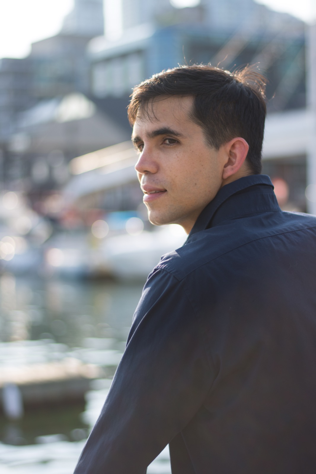 Client session photo: man in a navy shirt glancing over his shoulder by the waterfront